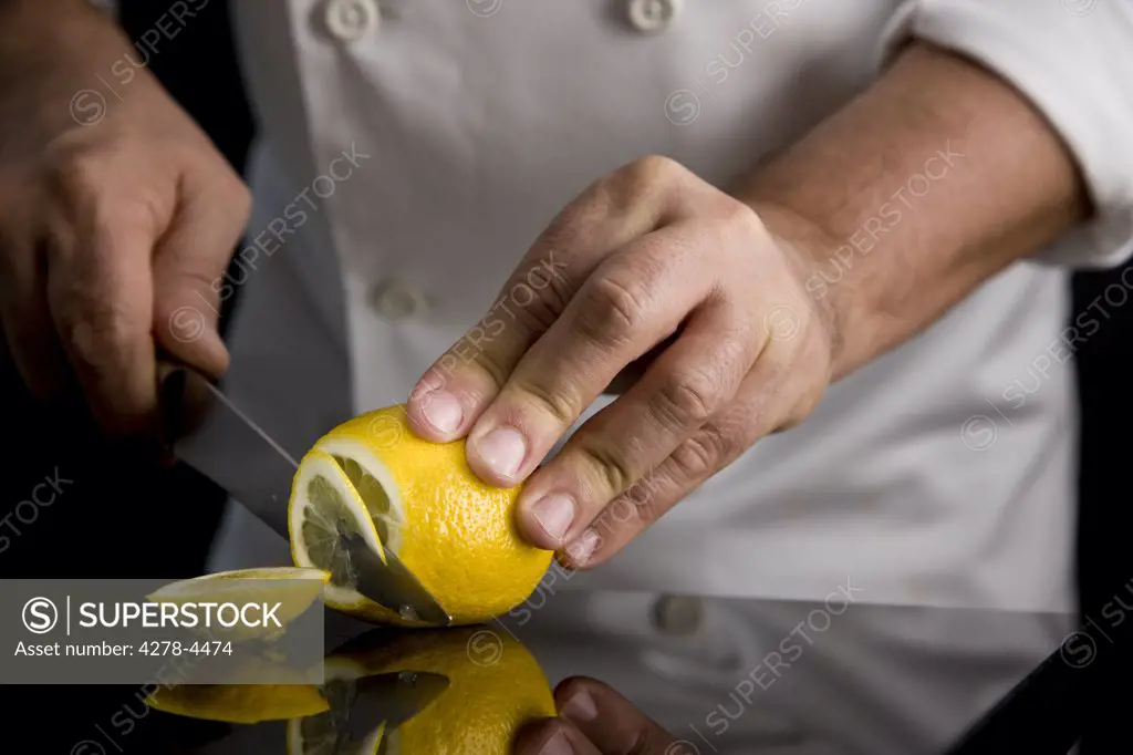 Close up of a chef hands slicing a lemon