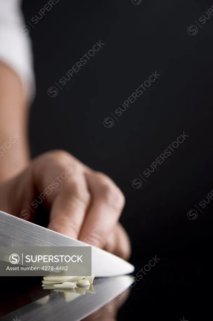 Close up of a chef hand slicing garlic