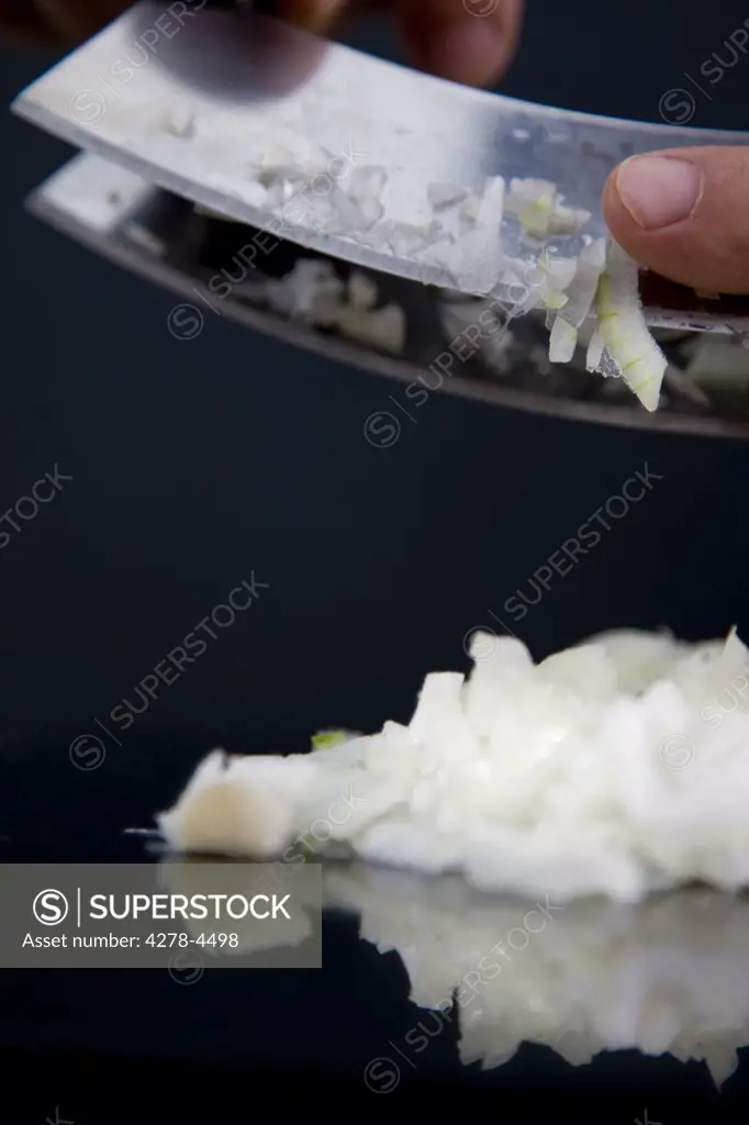 Close up of a chef hands chopping an onion with a double blade mezzaluna knife