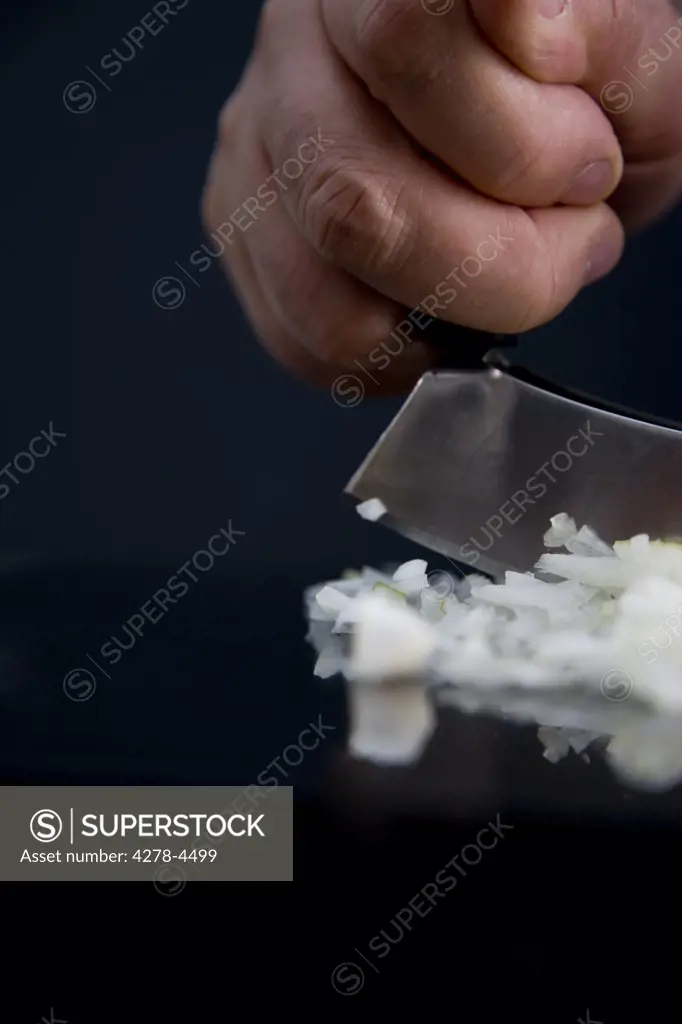 Close up of a chef hands chopping an onion with a double blade mezzaluna knife