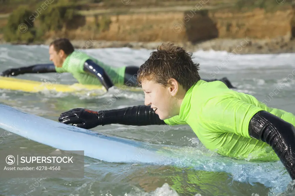 Teenage boy  lying on his surfboard paddling