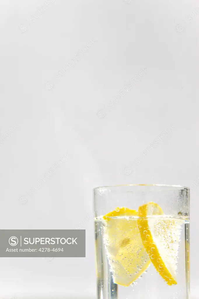 Close up of a glass of sparkling water and sliced lemon