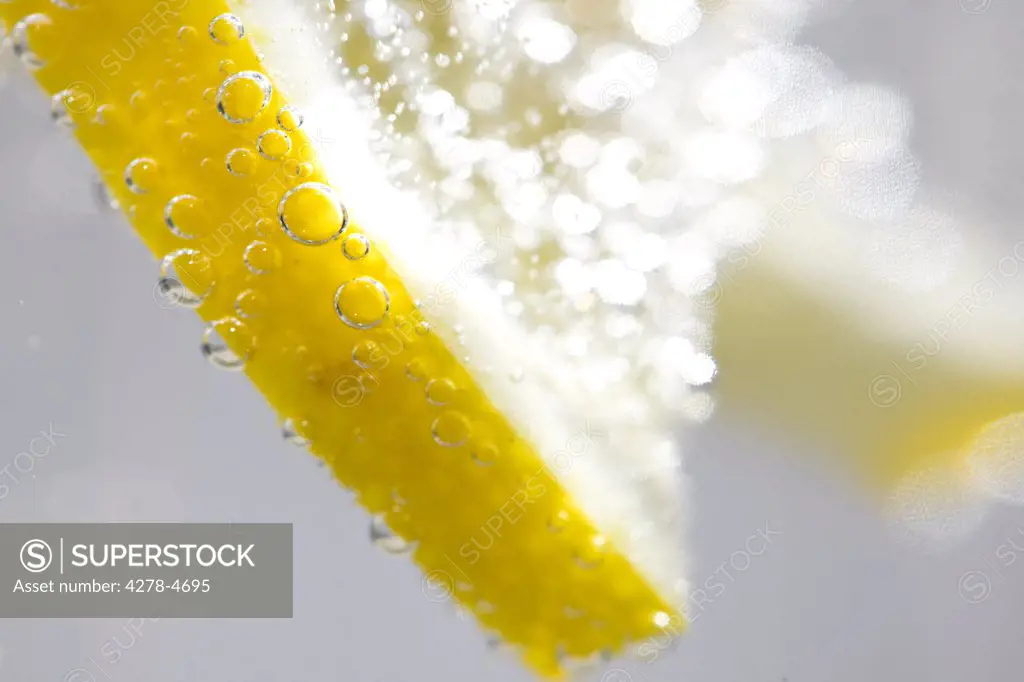 Extreme close up of a slice of lemon floating in sparkling water