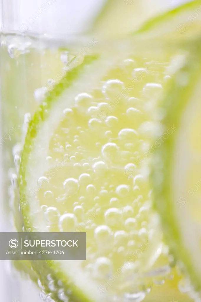 Extreme close up of slices of lime floating in sparkling water