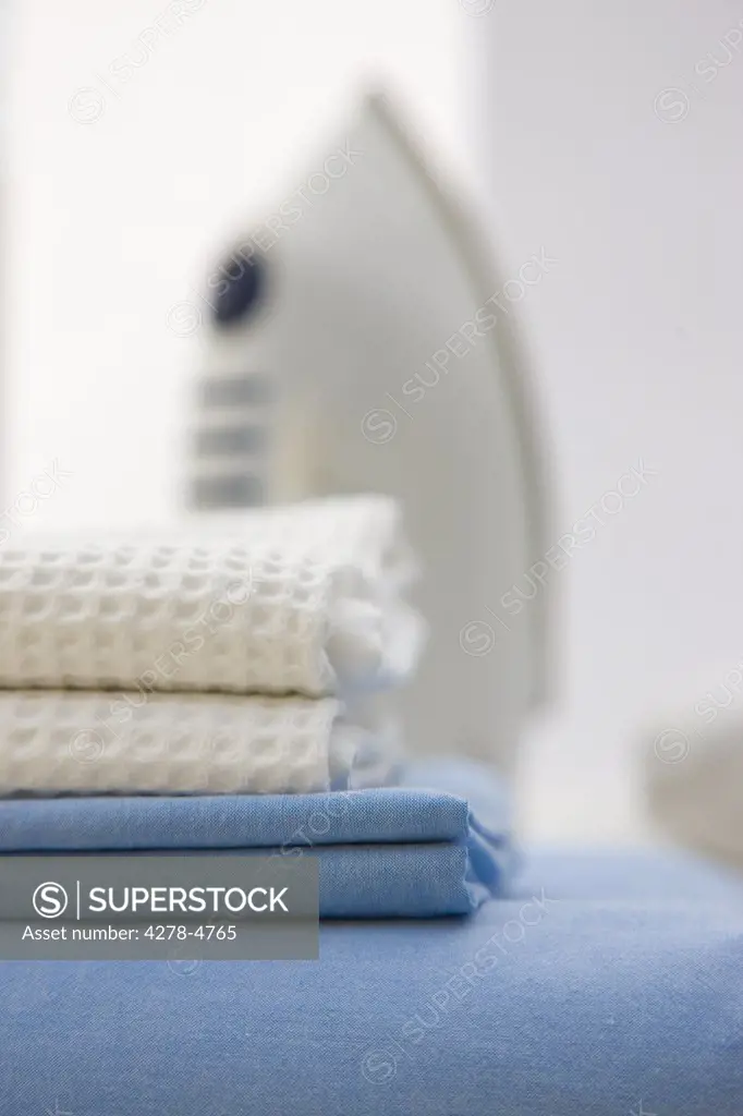 Close up of a stack of bed linen and an iron