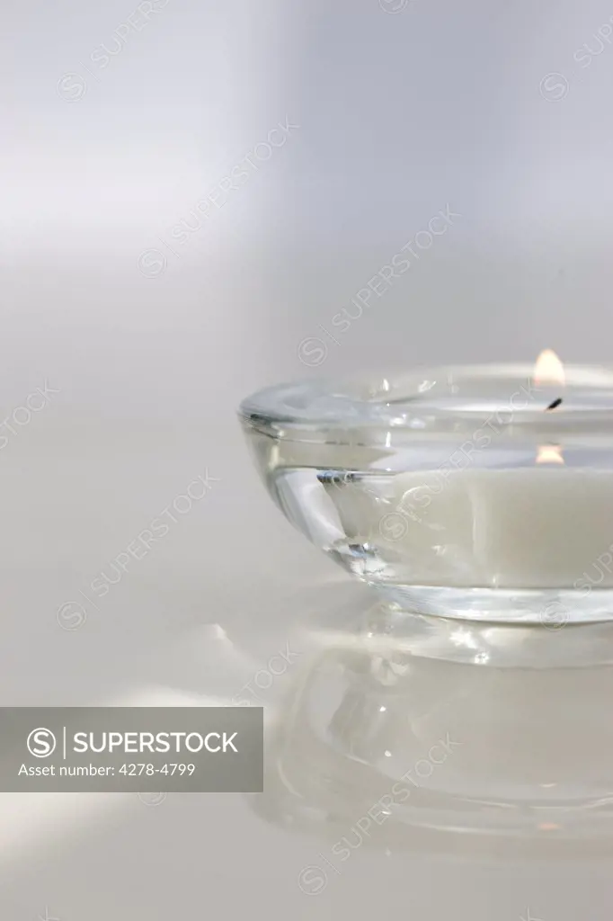 Close up of a burning tea light in a transparent glass holder