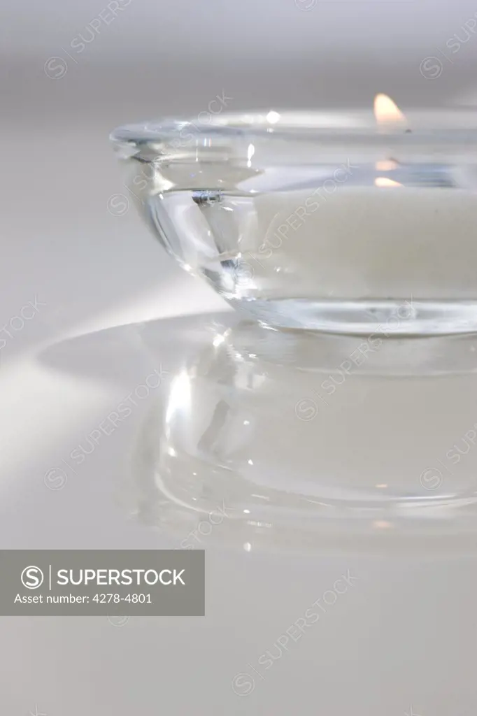 Close up of a burning tea light in a transparent glass holder
