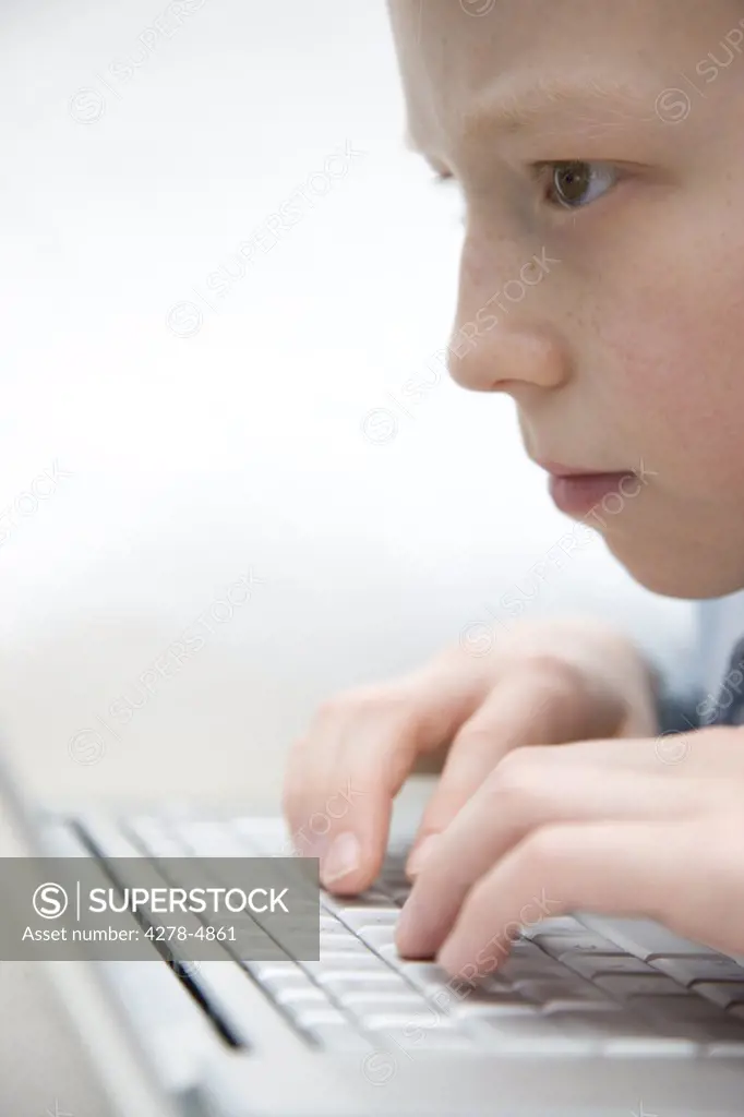 Extreme close up of a boy typing on laptop computer keyboard