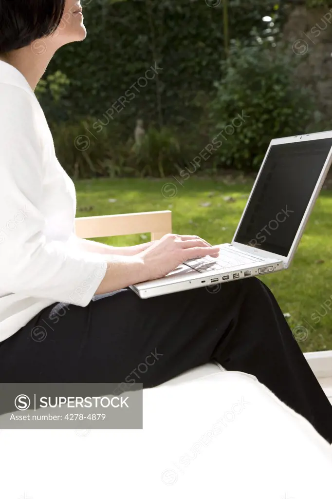 Woman sitting and typing on a laptop computer
