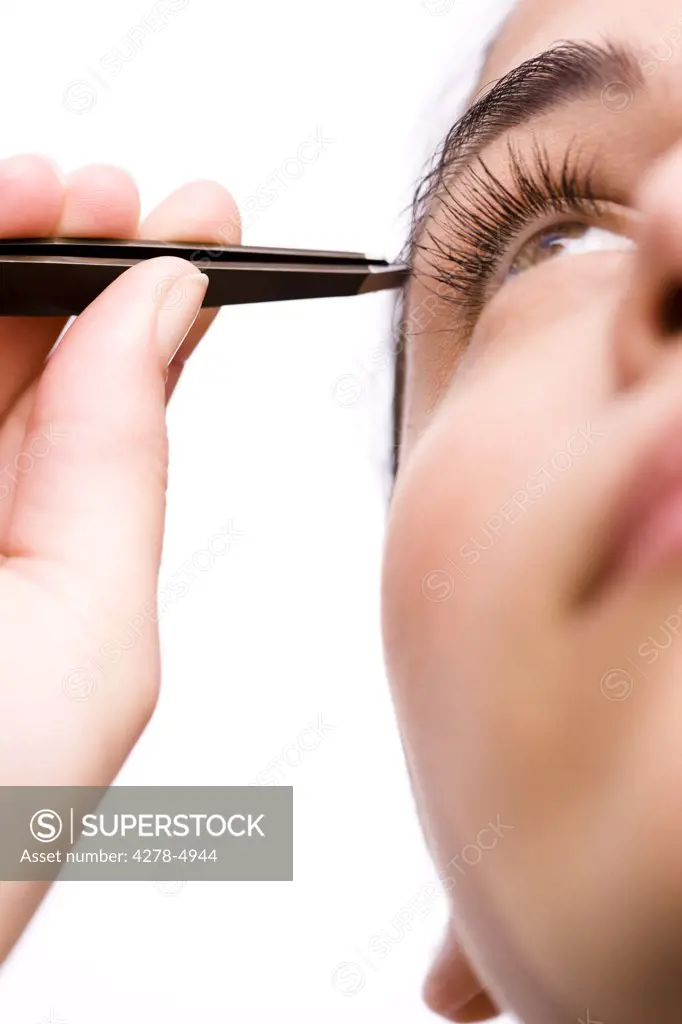 Extreme close up of a woman plucking her eyebrow with tweezers