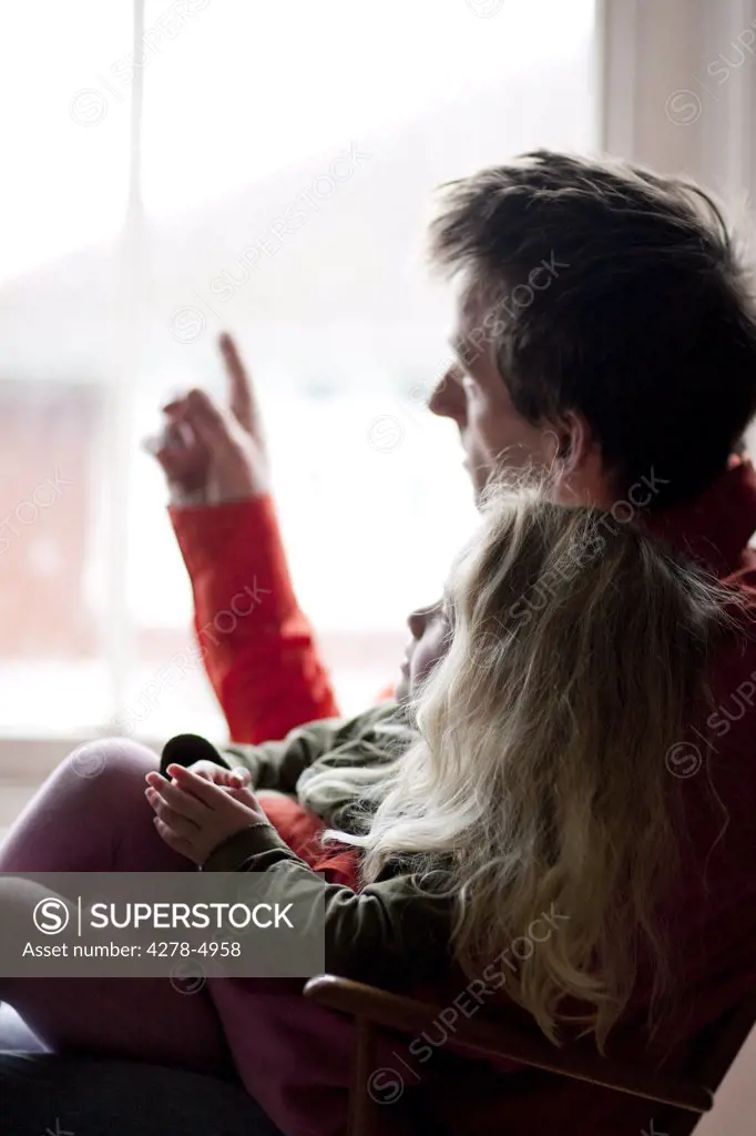 Man with a girl on his lap looking out of a window