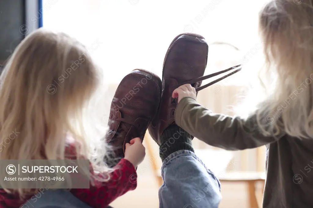 Back view of two girls unfastening a man shoes