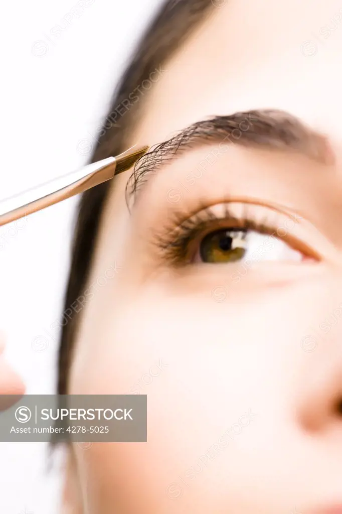 Extreme close up of a woman applying make up on her eyebrow