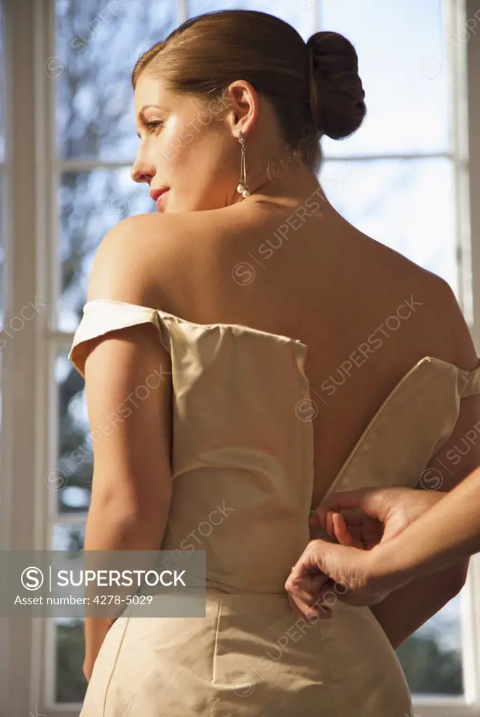 Woman hands unzipping the back of a bride wedding gown