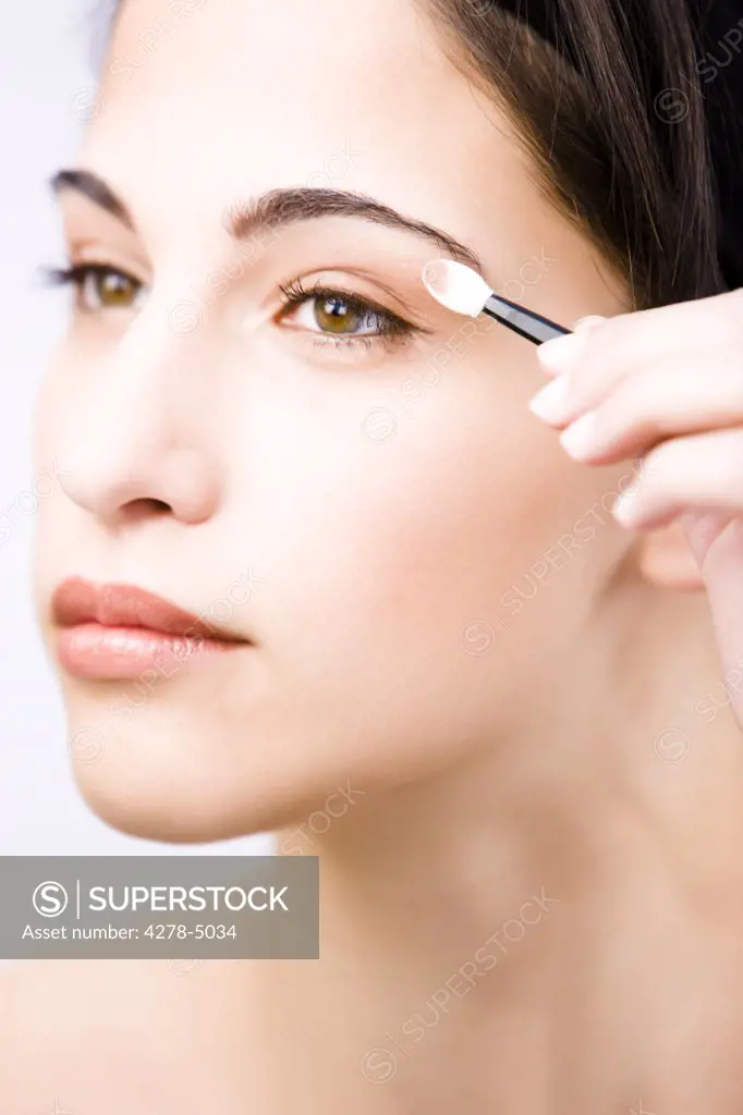Profile up of a young woman applying eyeshadow - close up