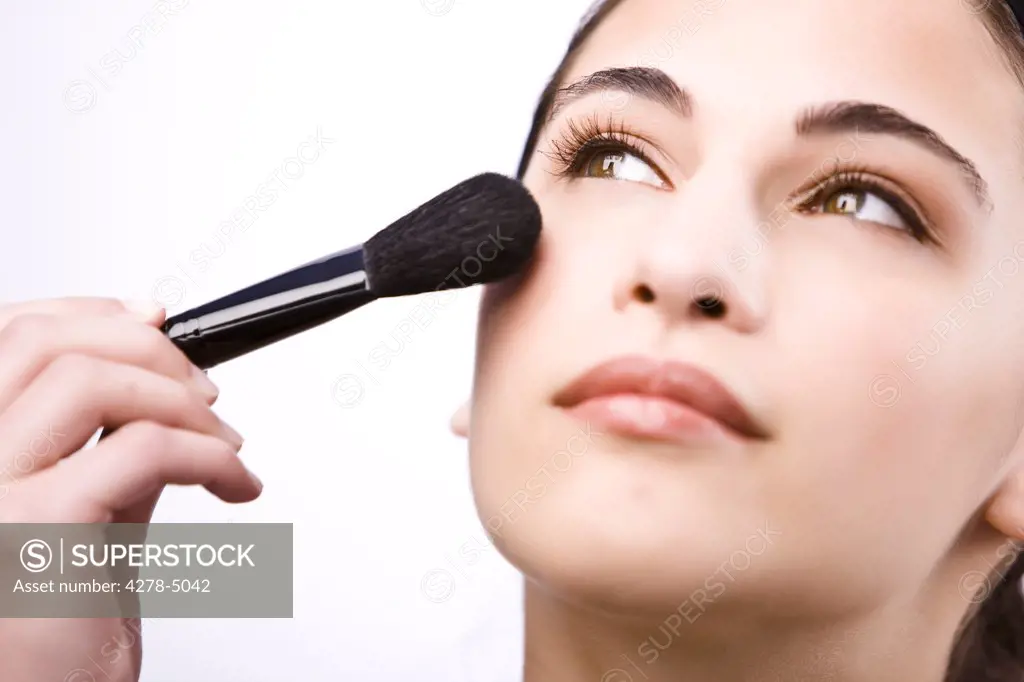 Close up of a young woman applying make with a blush brush