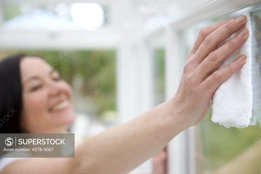 Smiling woman cleaning a window
