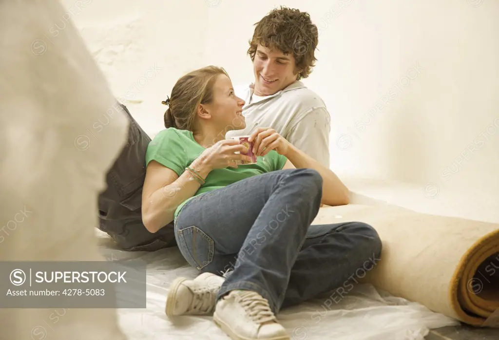 Couple leaning on a rolled up carpet looking at each other