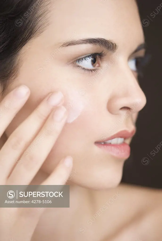 Close up of a woman applying moisturizer on her face