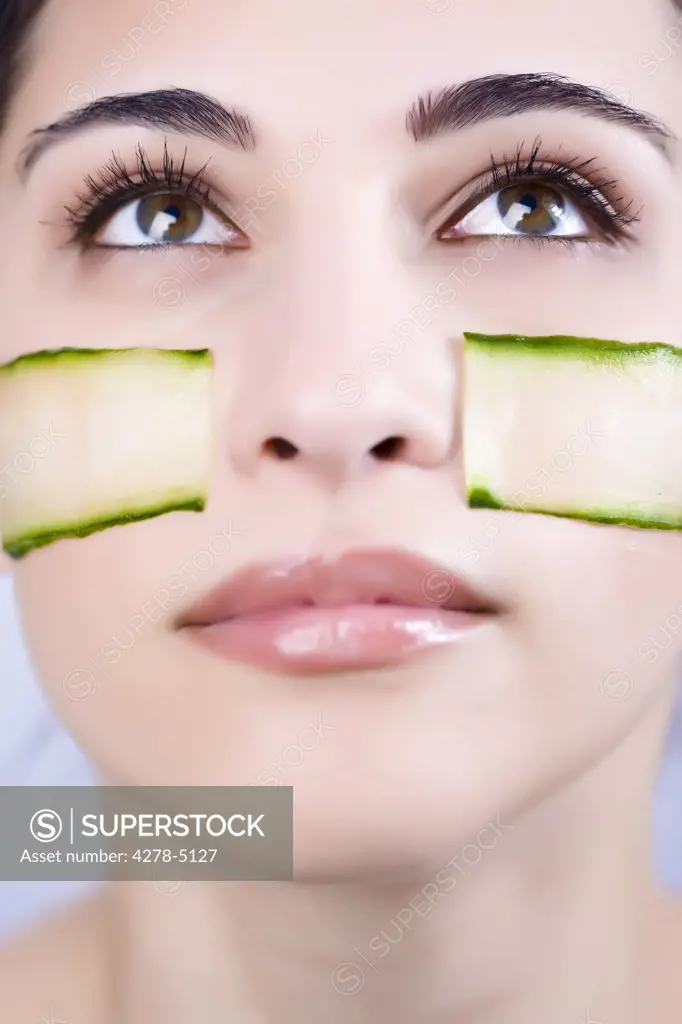 Close up of a young woman with cucumber slices on her cheeks