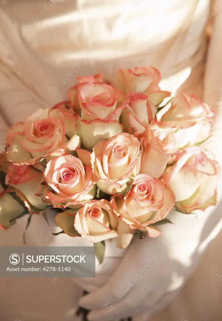 Close up of a bride gloved hands holding a bouquet of roses