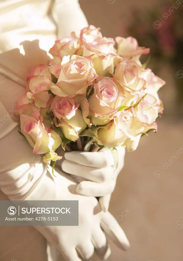 Close up of a bride gloved hands holding a bouquet of roses