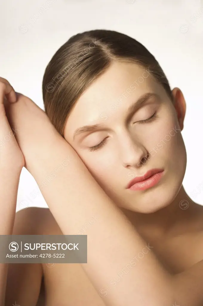 Woman with eyes closed resting her face on her arms