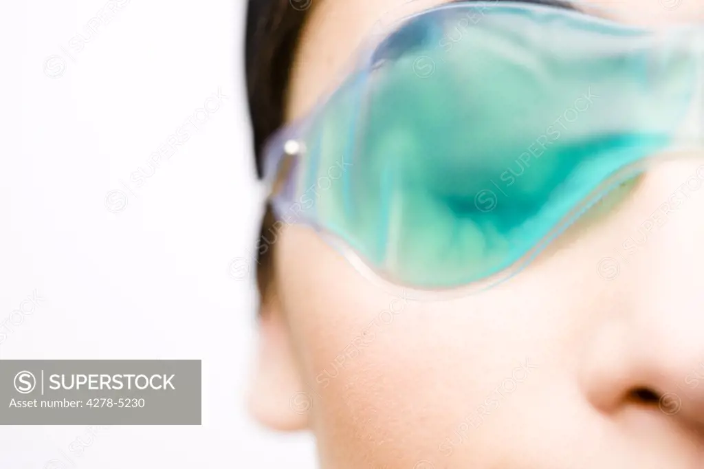 Extreme close up of a woman wearing a cooling eye mask - half face