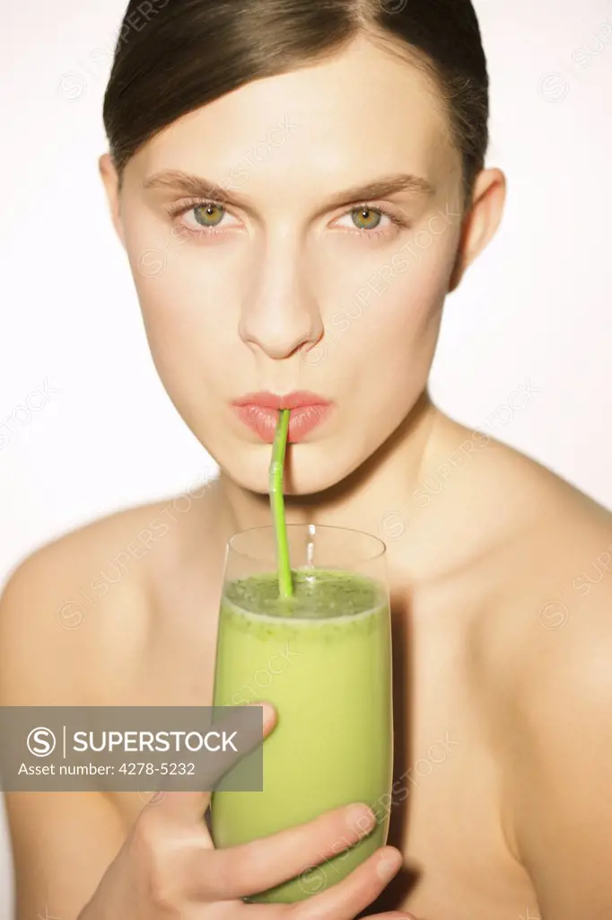 Woman drinking a vegetable smoothie with a straw