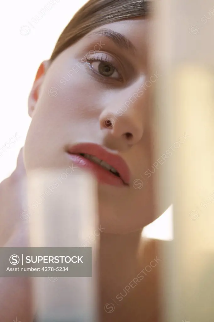 Close up of a woman partly covered by out of focus glass objects