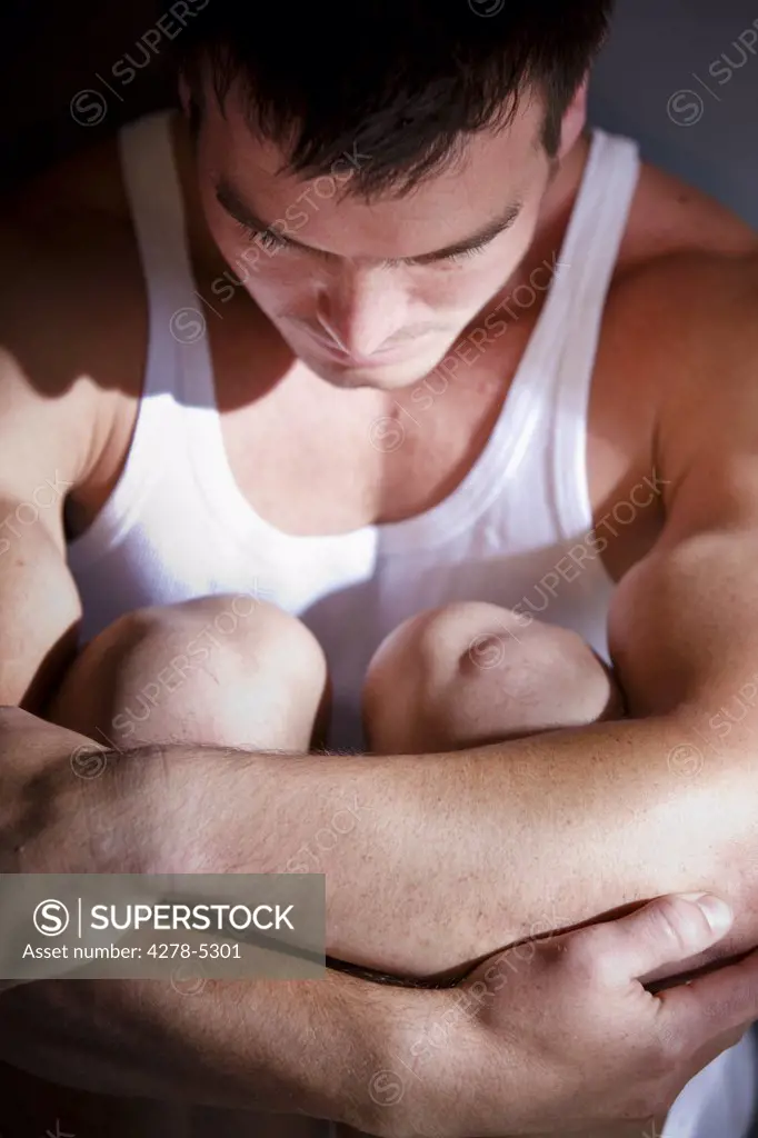 Man holding his knees above his chest
