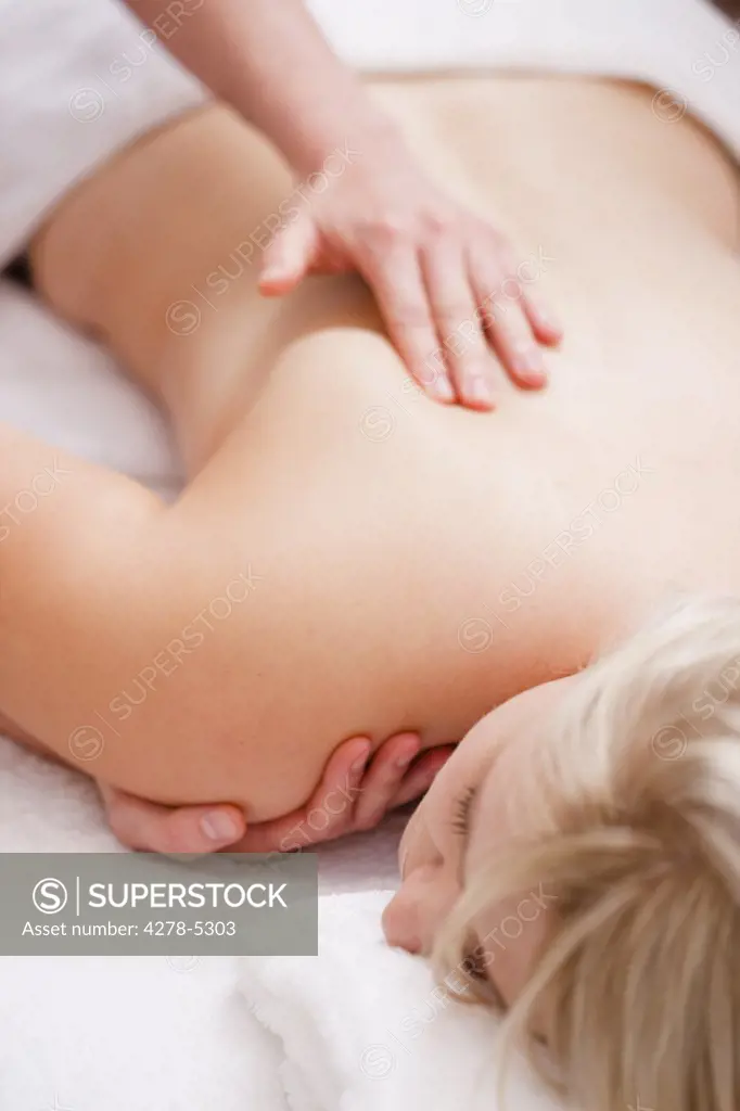 Masseur hands giving a woman a shoulder massage
