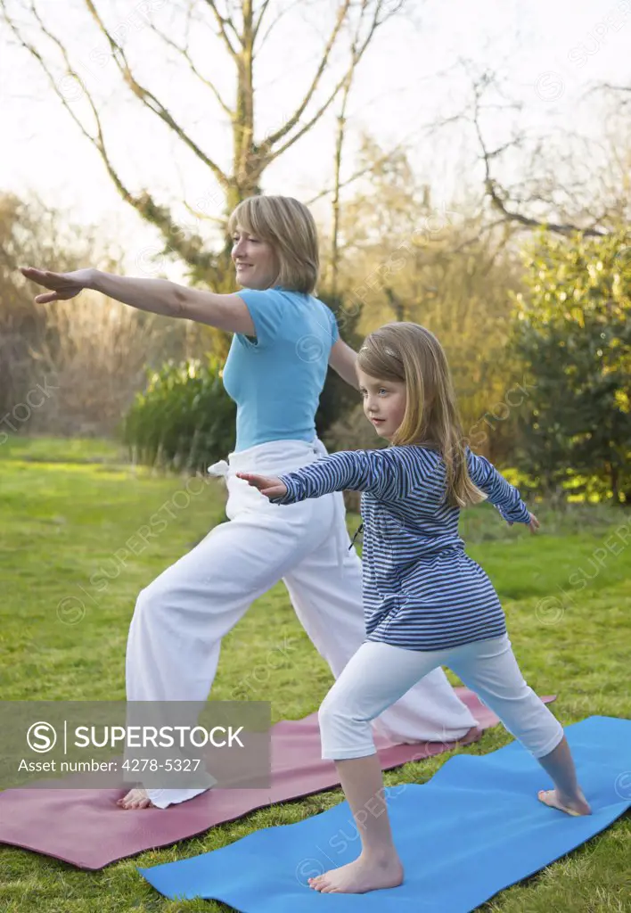 Mother and daughter practicing yoga in the garden