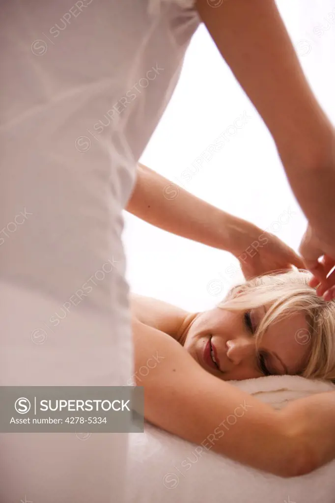 Back view of a masseuse giving a woman a head massage