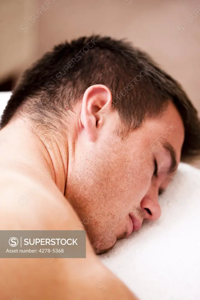 Close up of a man lying on his stomach with his eyes closed
