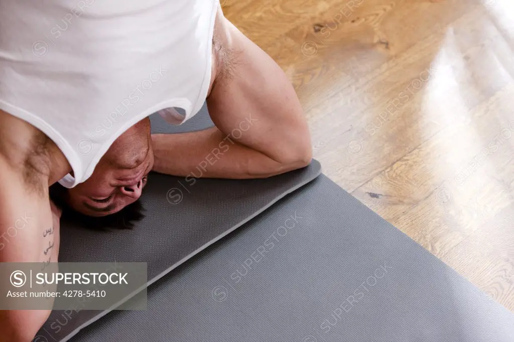 Man practicing yoga in the head-stand position