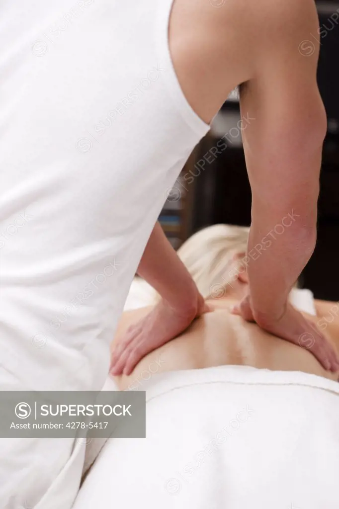 Back view of masseur giving a woman a back massage