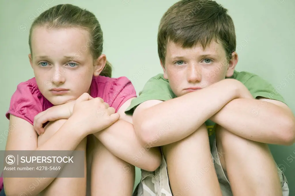 Boy and a girl sitting and holding their knees