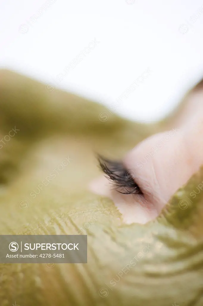 Extreme close up of a woman with green facial mask - profile
