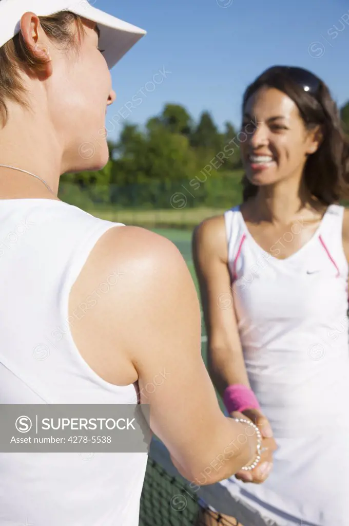 Two female tennis players shaking hands over the net