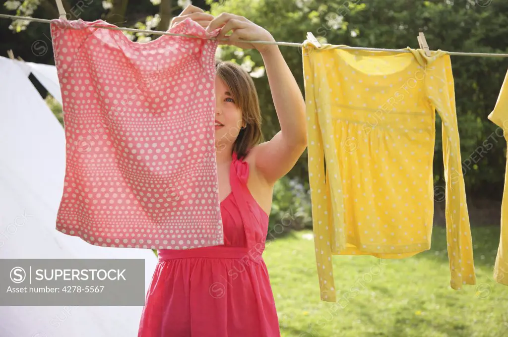 Teenaged girl hanging t-shirts on a clothesline