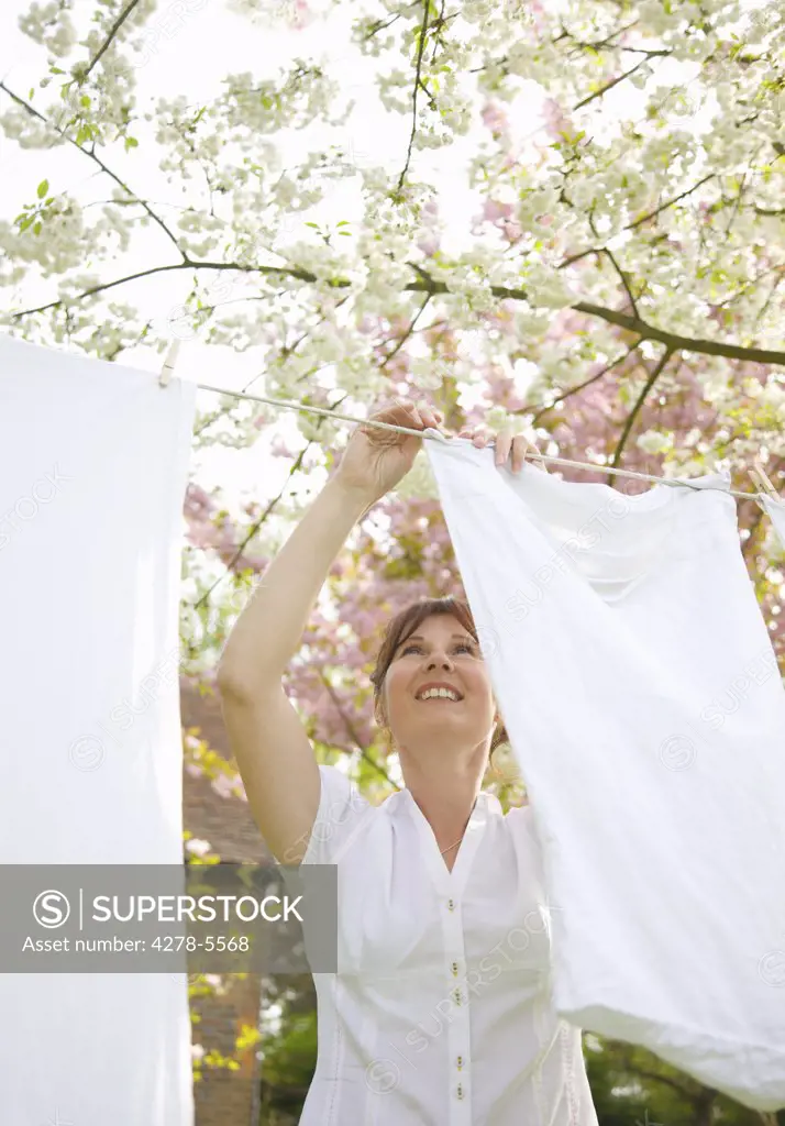 Smiling woman hanging linens on a clothesline