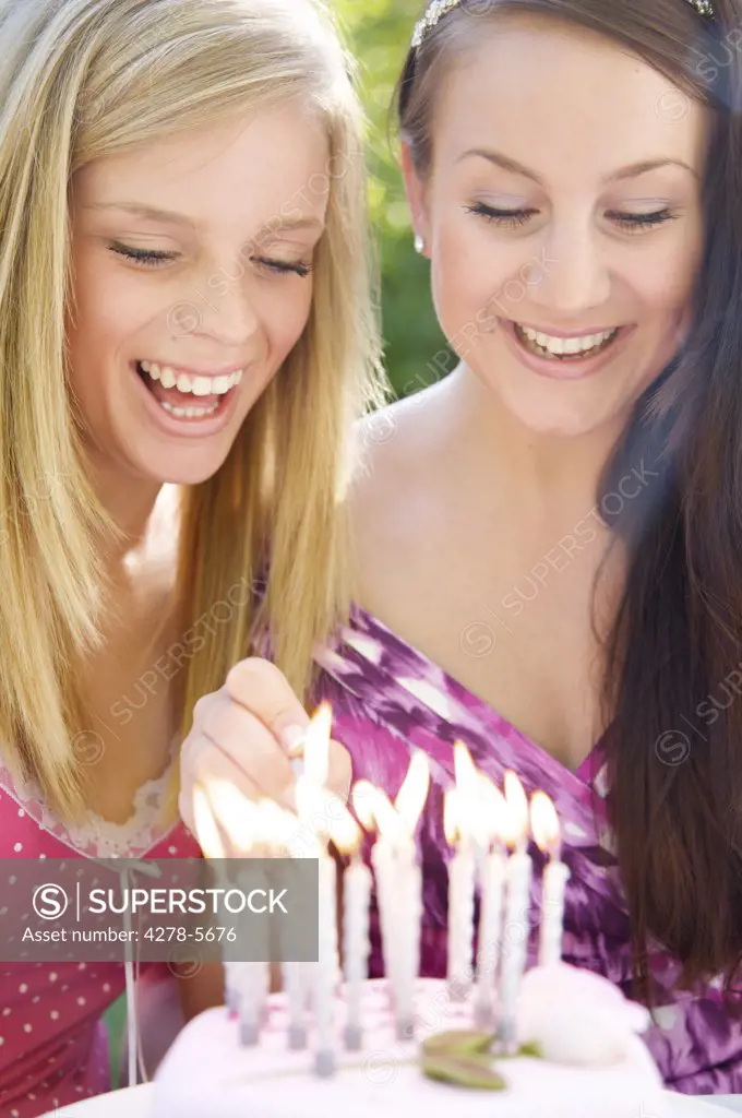 Girls lighting candles on a birthday cake