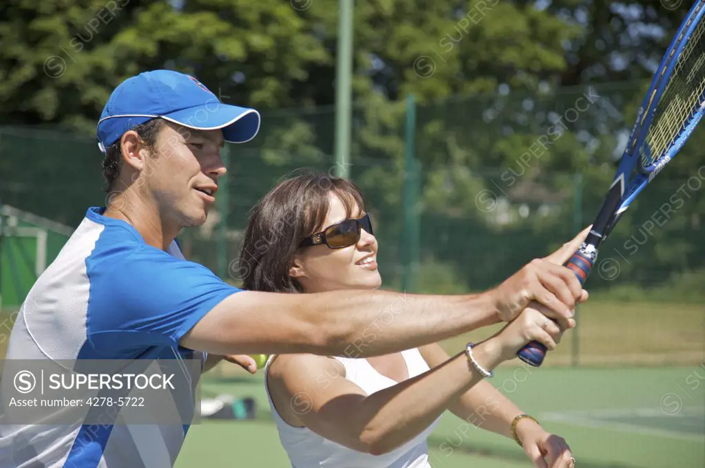 Tennis teacher instructing a woman