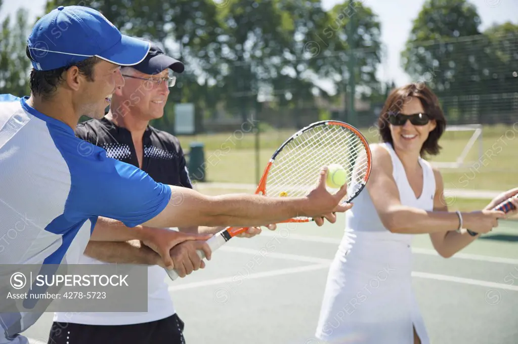 Tennis teacher instructing a couple