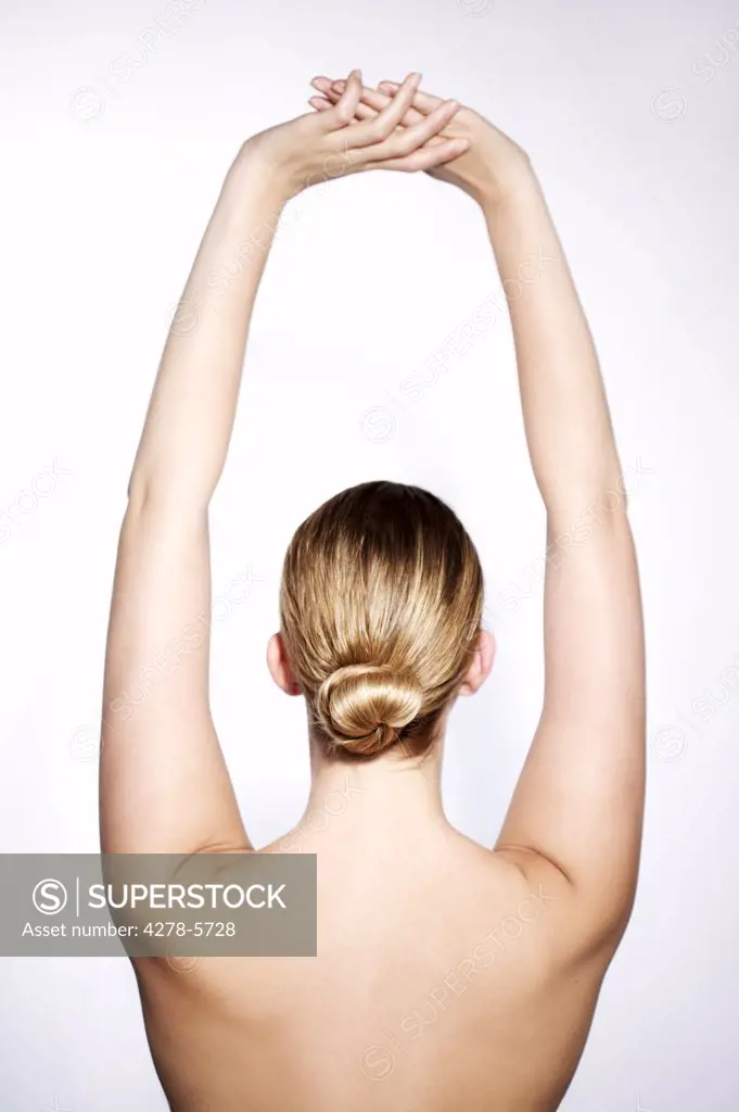 Back view of a young woman with her arms stretched above her head