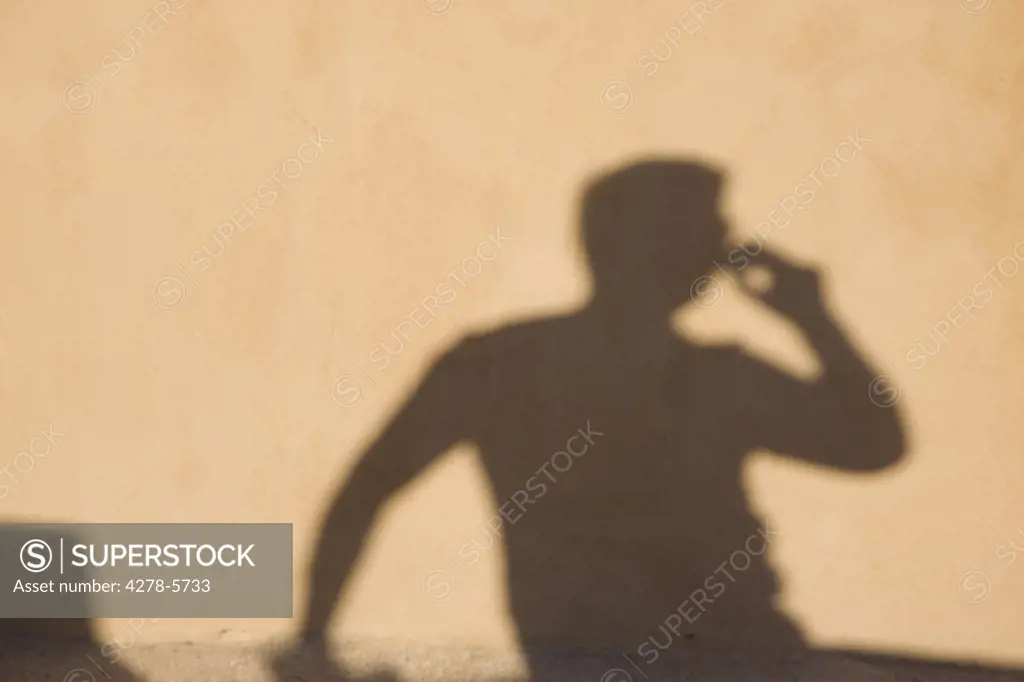 Shadow on a wall of a man using a cell phone