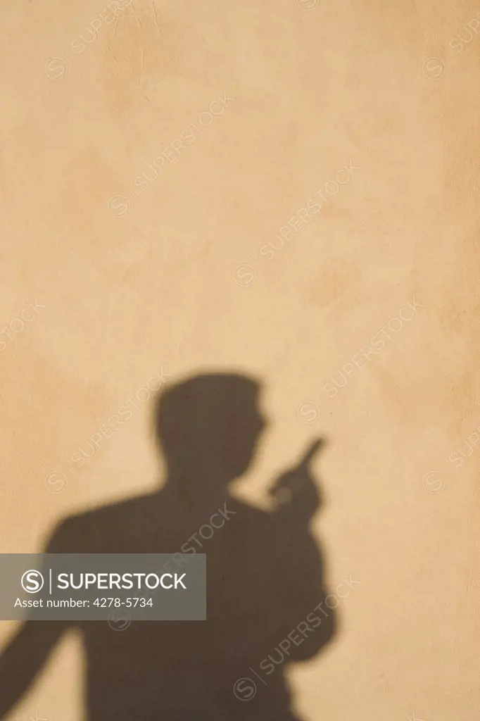 Shadow on a wall of a man using a cell phone