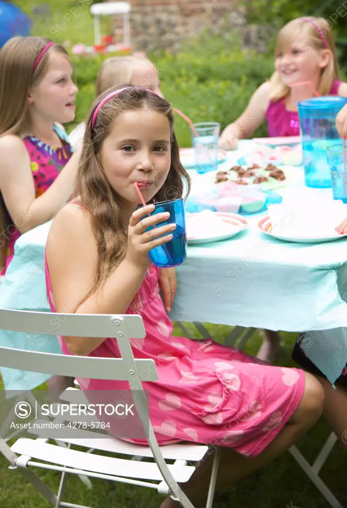 Young girl drinking from a straw at a garden party