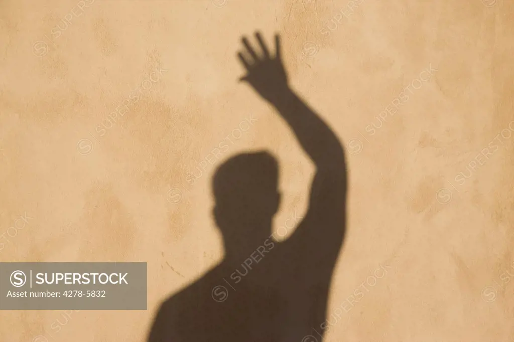 Shadow on a wall of a man waving his hand